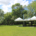 Photo of three white gazebios surrounded by green grass and trees