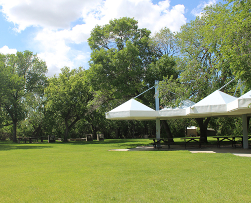 Photo of three white gazebios surrounded by green grass and trees