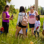 A group of people look at a turtle being held by a person.